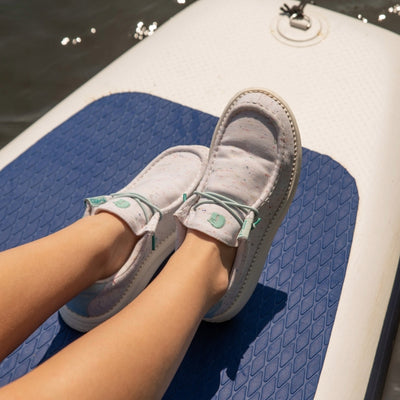 Woman wearing Camp Shoes sitting on the lake on a paddle board