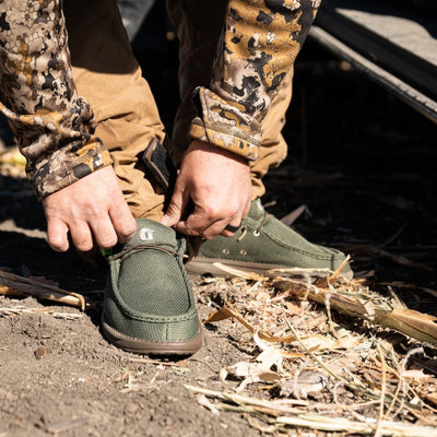 Man in the outdoors wearing a pair of olive colored Camp Shoes