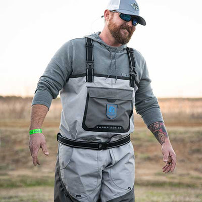 A man walking through a field wearing grey, uninsulated waders from Gator Waders. 