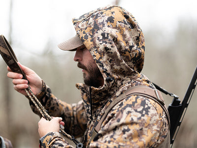 Man in 7 brown camo catahoula hoodie holding arrows