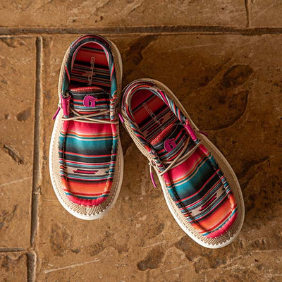 A pair of Gator Waders Camp Shoes in a Serape pattern sitting on on a tile floor.