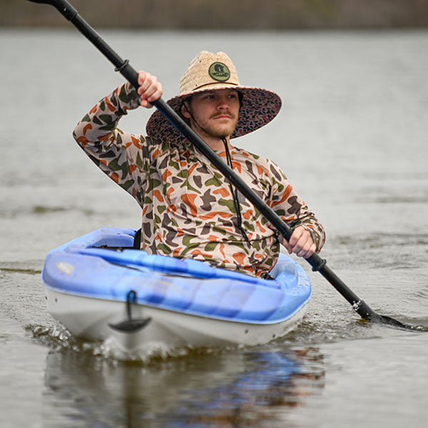 man in kayak wearing an old school camo straw hat