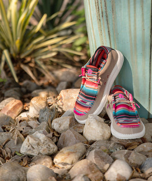 A pair of Gator Waders Camp Shoes sitting on rocks. The shoes are a Serape pattern.